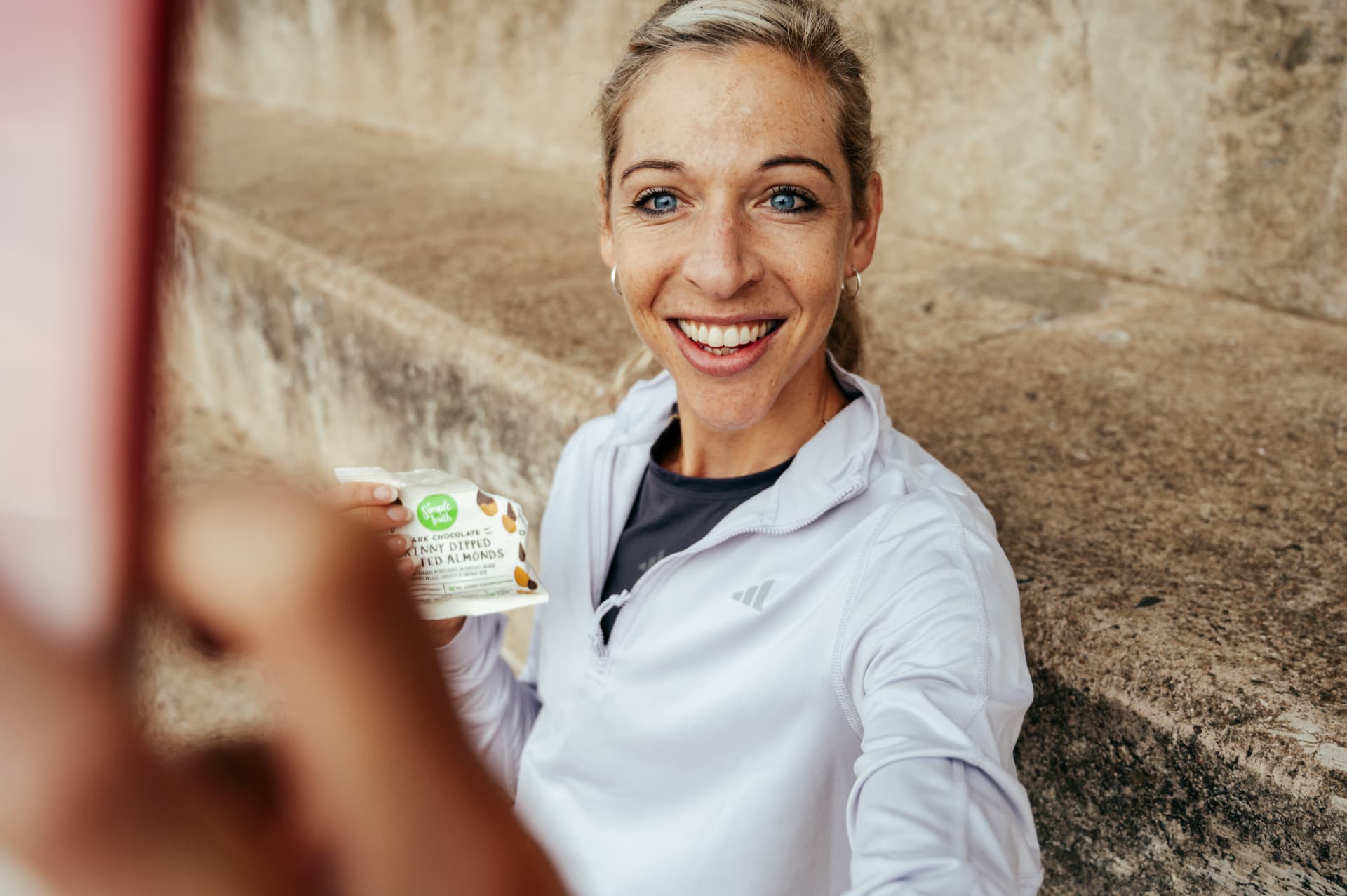 Athlete holding a snack packet on outdoor steps
