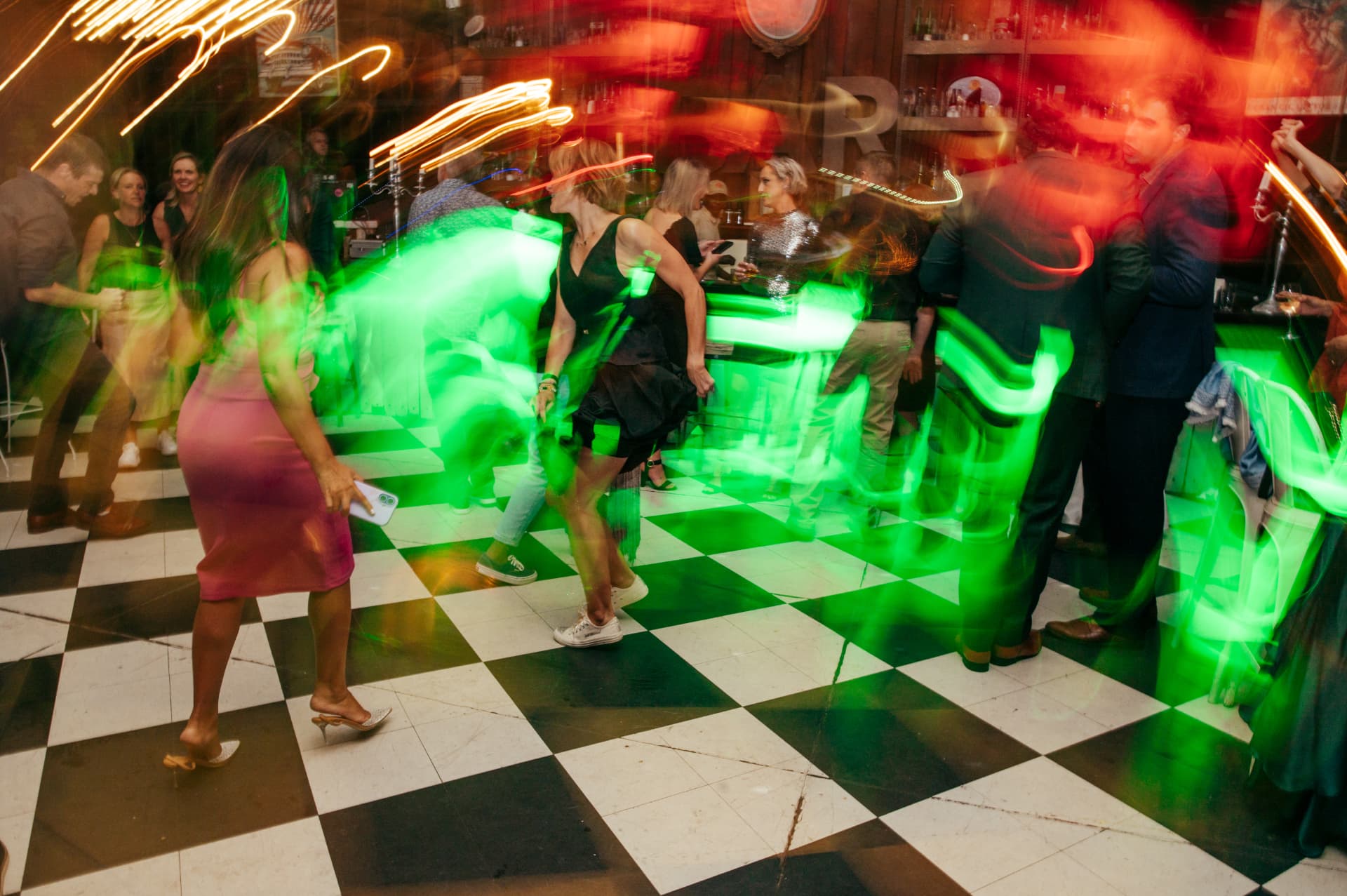Dancers on a checkered dance floor with drag-shutter light trails
